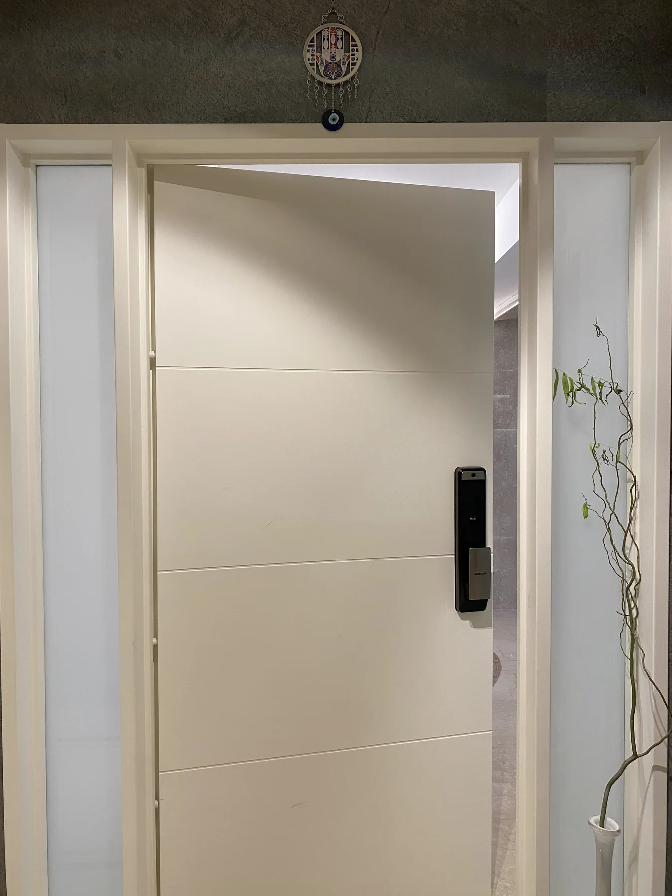 Puerta blanca abierta con cerradura digital en una instalación real