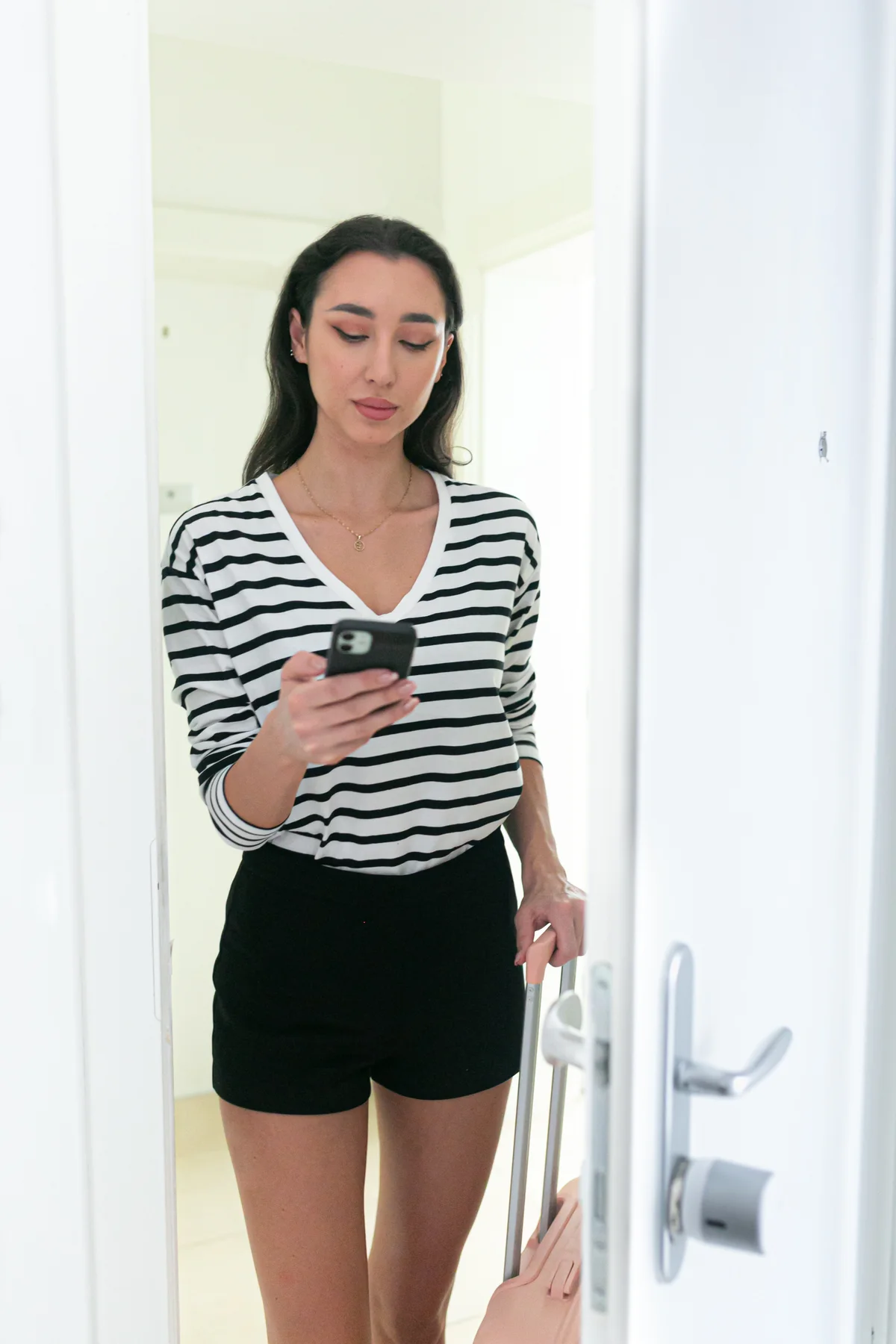 Persona consultando el celular junto a una puerta blanca