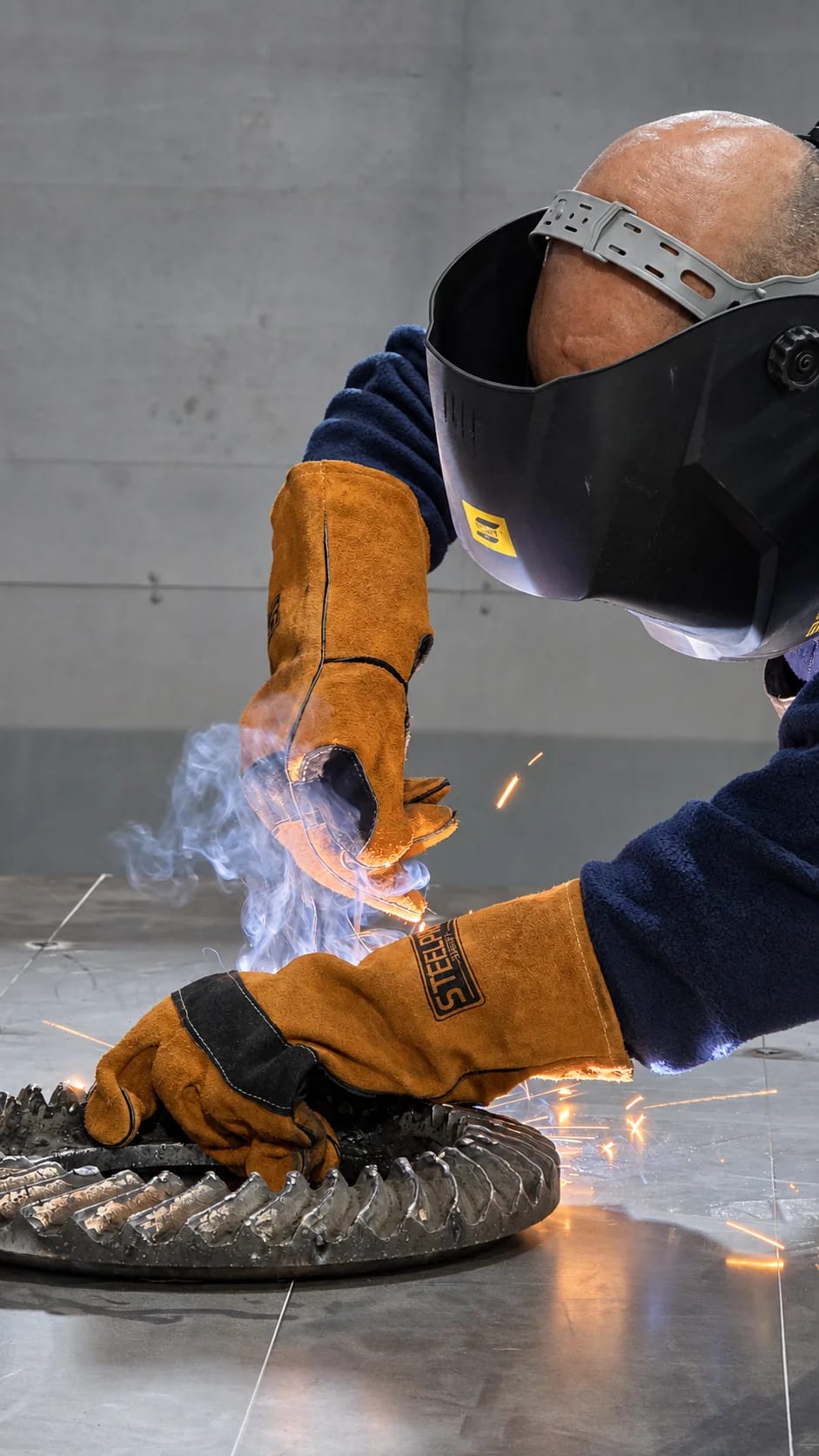 Operario con máscara y guantes soldando una pieza de acero en el taller de Superlock